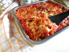 a casserole dish with meat and cheese in it on a table next to a cup