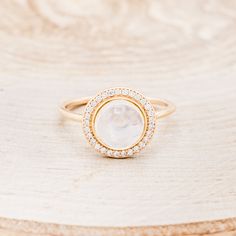 Ring Style: The "Terra" is a round cut moonstone women's engagement ring with a diamond halo Center Stone: 8mm Round Cabochon Cut Moonstone Accent Stones: 1/6ctw (29) 1mm Round Diamonds Available In: 14K White Gold, 14K Yellow Gold, or 14K Rose Gold Customizable: Because each ring is handcrafted to order we can customize center or accent stones, use unique materials, customize design features, or even use your own personal materials that you send us! To discuss your own customizations please fee Yellow Gold Diamond Moonstone Ring With Halo, 14k Gold Moonstone Ring With Halo, 14k Gold Round Moonstone Ring With Halo, Yellow Gold Moonstone Ring With Halo For Gift, Rose Gold Moonstone Ring, Rainbow Moonstone Engagement Ring, Spiritual Gold Moonstone Cabochon Ring, Moonstone Engagement Ring Rose Gold, Moonstone Engagement