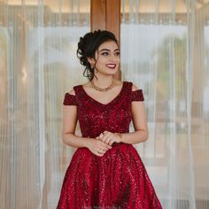 a woman in a red dress posing for the camera with her hands on her hips