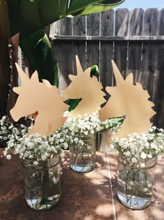 three vases filled with white flowers and cut out sunbursts on top