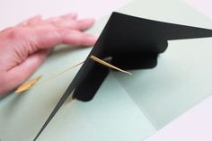 a person is holding a piece of black paper with gold pins sticking out of it