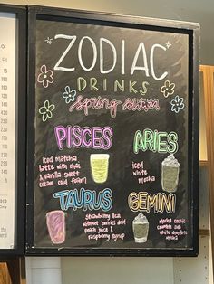 the menu for zodiac drinks is written on a blackboard in front of a sign