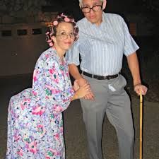 an older man and woman standing next to each other with a cane in their hands