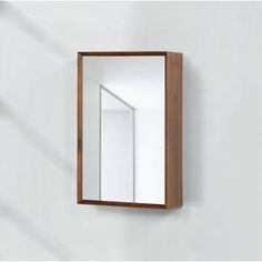 a mirror mounted to the side of a white wall next to a wooden framed object