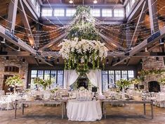 a large room with tables and chairs covered in white linens, flowers and greenery