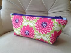 a pink and green flowered purse sitting on top of a white chair