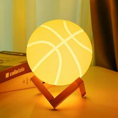 a basketball sitting on top of a table next to a stack of books and a lamp