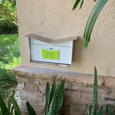 a mailbox with the number thirteen on it is next to some plants and trees