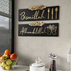 two black and gold signs on the wall above a bowl of fruit