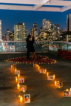 two people standing next to each other in front of candles and pictures on the ground