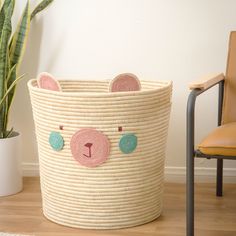 a bear shaped basket sitting on top of a wooden floor next to a potted plant