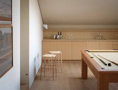 a pool table and two stools in a room with wood flooring on the walls