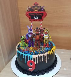 there is a birthday cake decorated with monsters and candy on the bottom layer, along with an age 9 sign