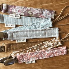 four different colors of fabric with tags attached to them on a wooden surface, including blue, pink, and white flowers