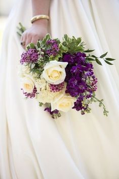 a bridal holding a bouquet of purple and white flowers