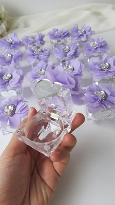 a person is holding a small glass box with flowers in it and some diamonds on the lid