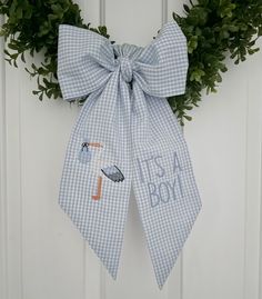 a blue and white gingham bow hanging on a door with the words it's a boy