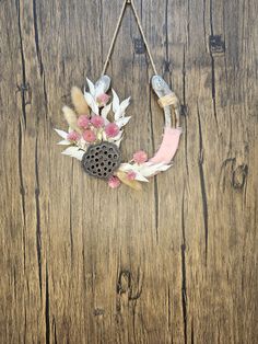 a wreath with flowers and feathers hanging on a wooden wall