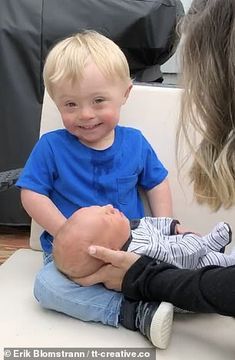 a woman holding a baby in her lap and smiling at the child's face