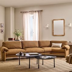 a living room filled with furniture and a large mirror on the wall above it's windows