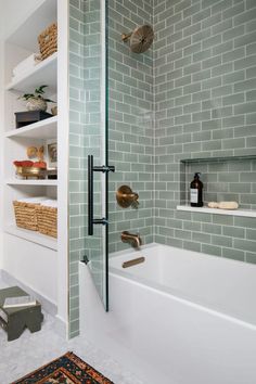 a white bath tub sitting next to a walk in shower under a bathroom mirror with shelves above it