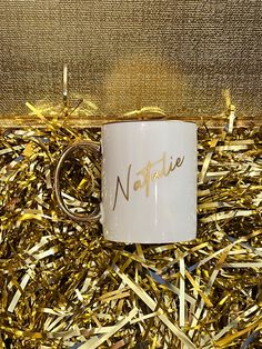 a white coffee mug sitting on top of gold tinsel