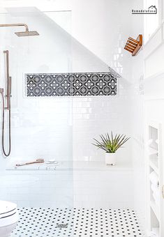 a white tiled bathroom with black and white floor tiles on the walls, shower head, and toilet