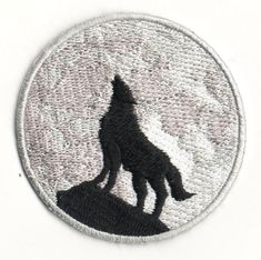 a black and white patch with a wolf silhouette on it's side, in front of a cloudy sky