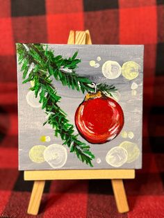 an acrylic painting of a christmas ornament hanging from a tree branch