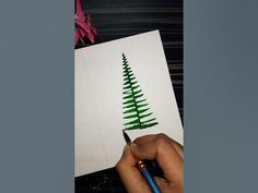 someone is drawing a christmas tree with green crayon pencils on white paper