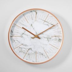 a marble clock with gold hands on a white wall