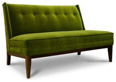 a green couch sitting on top of a white floor next to a wooden leg chair