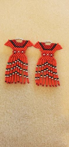 two red and black beaded earrings sitting on top of a white carpeted floor