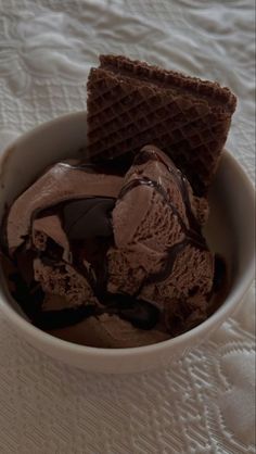 a bowl filled with chocolate ice cream and waffles on top of a table