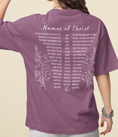 a woman wearing a purple t - shirt with names of christ printed on the back