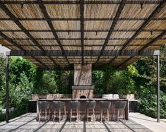 an outdoor dining area with tables and chairs under a straw covered roof, surrounded by greenery