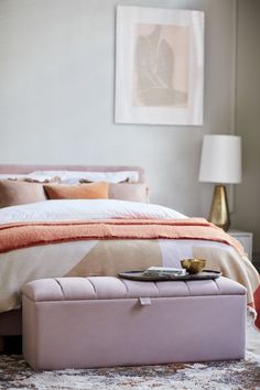 a bedroom with a bed, ottoman and pictures on the wall above it is shown