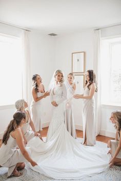 bridesmaids helping the bride put on her wedding dress