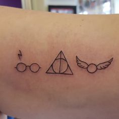 a harry potter tattoo on the back of a woman's arm, which has three symbols