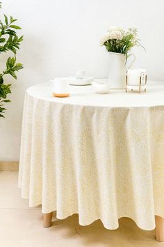 the table is set with two white cups and saucers on it, along with a potted plant