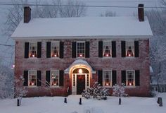 a red brick house covered in snow with christmas lights on the windows and shutters