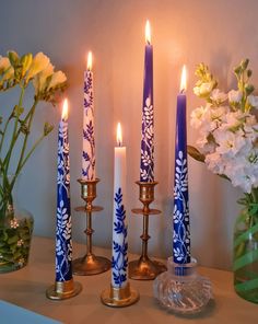 candles are lit on a mantle with flowers in the background