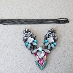 a pair of colorful jeweled necklaces sitting on top of a white counter next to a black tie