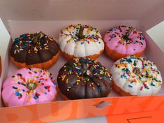 there are six donuts in the box with sprinkles on them,