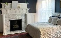 a bedroom with a bed, fireplace and rug in front of the fire place on the wall