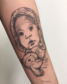 a small tattoo on the arm of a baby with a teddy bear in its arms