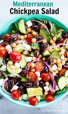 a salad with cucumbers, tomatoes, olives and chickpea in a blue bowl