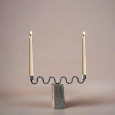 two candles are lit in the middle of a stone block with one candle on it's end