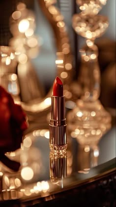 a red lipstick sitting on top of a table next to wine glasses and candle holders