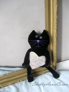 a stuffed black cat sitting in front of a mirror with a message written on it